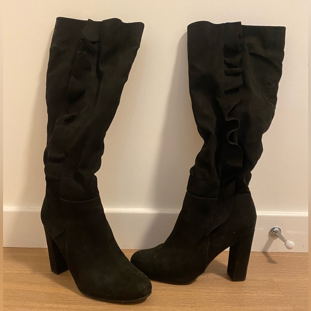 Knee-high heeled black suede boot line with outside frills